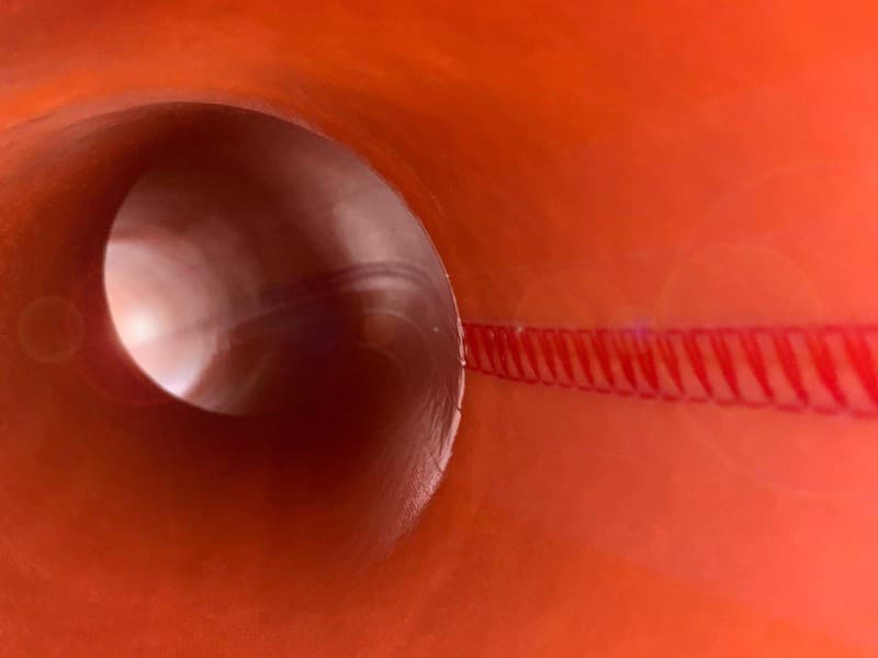 Worker installing blue pipes in excavated area