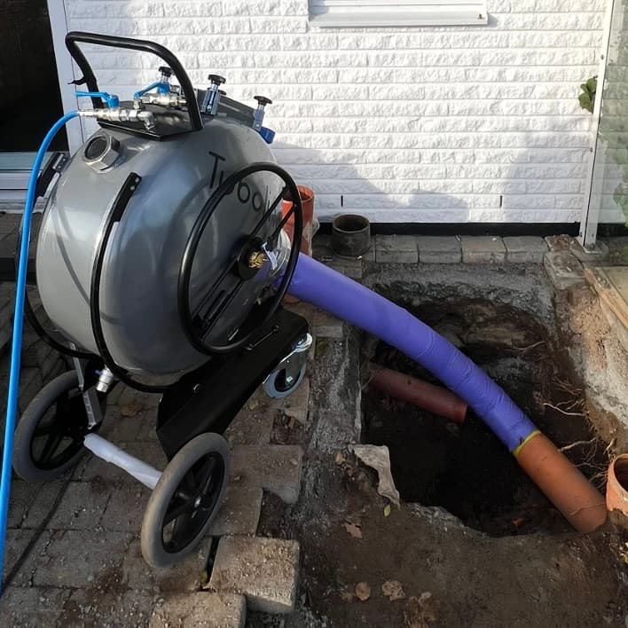 Professional pipe relining technician working with specialized equipment in an excavated area, demonstrating the pipe relining process